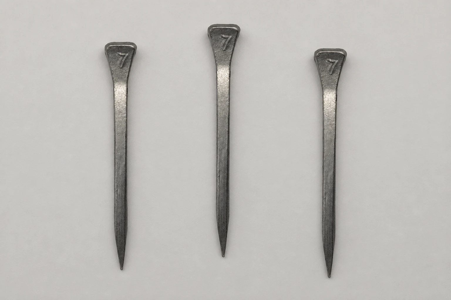Three steel horseshoe nails showing the reference head and tapered shank